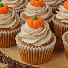 cupcakes with frosting and pumpkin decorations are on a wooden platter for display