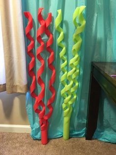 three red and green streamers sitting on the floor next to a blue drapes