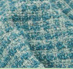 closeup of the texture of a blue and white tweed fabric, with green border