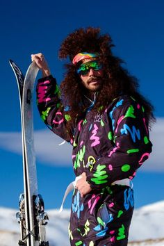 a man with long hair wearing skis on top of a snow covered slope,