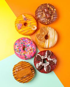 four donuts with different toppings are arranged on a multi - colored background,