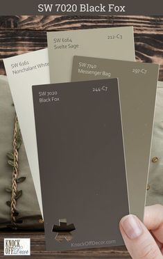 a hand holding three different color swatches for the sw700 black fox paint