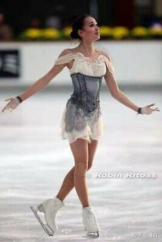 a woman skating on an ice rink wearing white and grey dress with short sleeves, lace detailing