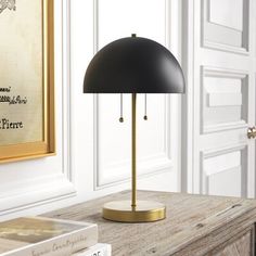 a black lamp sitting on top of a wooden table next to a white bookcase