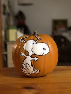 a pumpkin with a cartoon dog painted on it's side sitting on a table