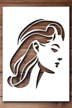 a woman's face with long hair cut out of paper on a wooden background