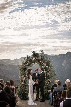 a bride and groom standing at the end of their wedding ceremony with mountains in the background