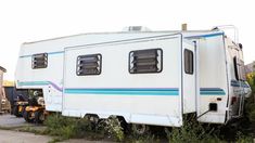 an rv parked on the side of a road next to a tree and building structure