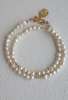 This is not your average pearl bracelet... Our Pearl Double Wrap Bracelet with white pearls features a double wrap style with with gold beaded accents. Wear solo or stacked with your favorite pieces!Materials: Medium pearls and gold filled beads with a gold plated coin ending. Length: Measures an adjustable 14-15" with an inch and a half extenderSKU: B1189GMaterials + Care Classic White Pearl Bracelet With Gold Beads, Gold Pearl Single Strand Beaded Bracelets, Adjustable White Pearl Necklace With 14k Gold Filled, Adjustable White Pearl Necklace In 14k Gold Filled, Adjustable Double Strand Gold Pearl Necklace, Gold Single Strand Pearl Bracelet With Round Beads, Gold Pearl Bracelet With Single Strand Of Round Beads, Everyday Gold Single Strand Pearl Bracelet, White Pearl Chain Bracelet In 14k Gold Filled