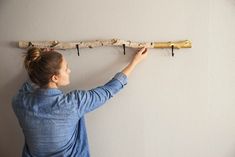 a woman is holding a long wooden stick with two keys on it and hanging from the wall