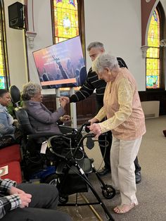 an elderly woman standing next to a baby stroller in front of stained glass windows