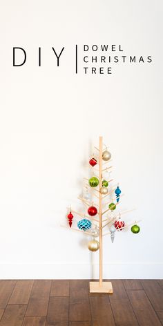 a small christmas tree with ornaments on it in front of a wall that says diy