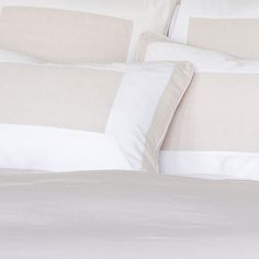 a bed with white and beige pillows on top of it