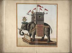 an elephant standing in front of a tower with flags on it's back legs