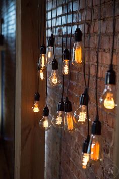 several light bulbs are hanging on a brick wall