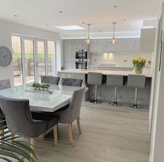 a dining room table with chairs and a clock on the wall in front of it