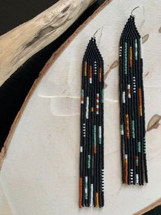 two pairs of beaded earrings sitting on top of a piece of wood