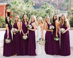 a group of women standing next to each other wearing purple dresses and holding bouquets