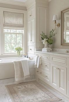 a large bathroom with white cabinets and bathtub in the center, along with a rug on the floor