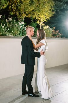 a man and woman standing next to each other in front of a tree at night