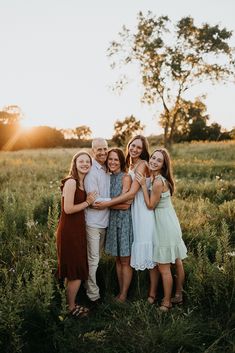 a group of people standing next to each other in a field with the sun setting behind them