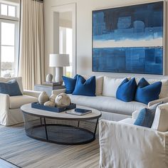 a living room filled with white furniture and blue pillows