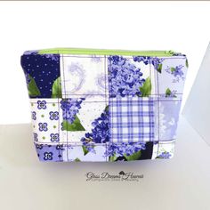 a blue and white patchwork bag with flowers on it, sitting on a table