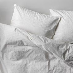 an unmade bed with white sheets and pillows