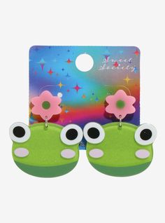 pair of green and pink monster earrings with large eyes on each ear, in front of a colorful background