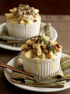 two white bowls filled with macaroni and cheese on top of a tablecloth