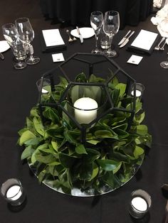 the centerpiece is surrounded by greenery, candles and place settings for guests to sit at