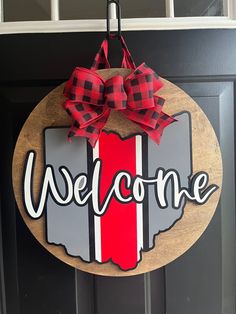 a welcome sign hanging on a door with a red ribbon around it and the word welcome