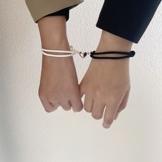 two people wearing bracelets holding hands with one hand and the other on their wrist