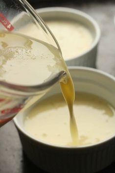 a person pours liquid into small white bowls filled with soup and cheesecake toppings