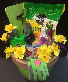 a green bucket filled with gardening supplies and flowers on top of a table next to a pair of gloves