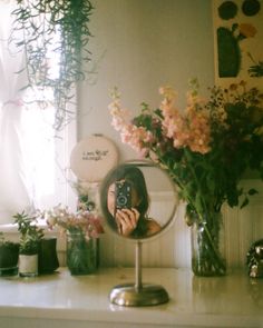 a woman taking a selfie in front of a mirror with flowers on the counter