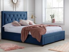 a bed with blue upholstered headboard and pillows