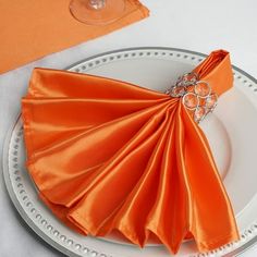 an orange napkin on top of a white plate