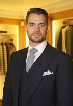 a man wearing a suit and tie standing in front of a closet