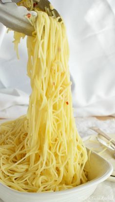 someone is lifting noodles from a white bowl