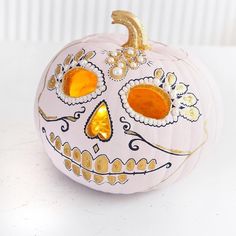 a white pumpkin decorated with gold and orange decorations