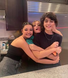 three people hugging each other in a kitchen