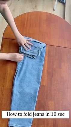 someone is folding their jeans on top of the table to fold them into a rectangle