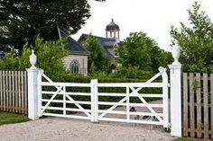 a white fence and gate in front of a house with a clock tower behind it