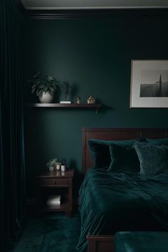 a bedroom with dark green walls and bedding, two shelves on either side of the bed