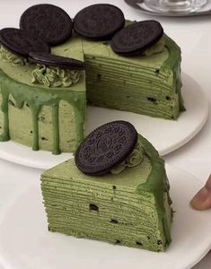 there is a green cake with oreo cookies on the top and one slice missing