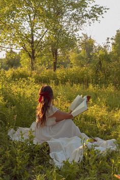 a woman sitting in the grass reading a book