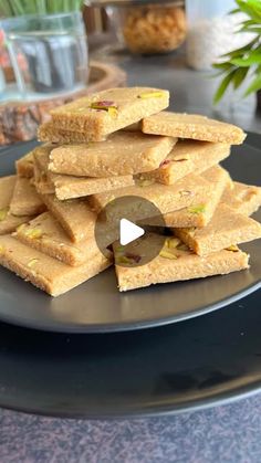 a black plate topped with lots of crackers on top of a table next to a potted plant