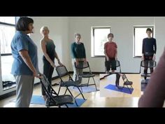 a group of people standing around each other in a room with yoga mats on the floor