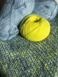 two skeins of yarn sitting next to each other on top of a blanket